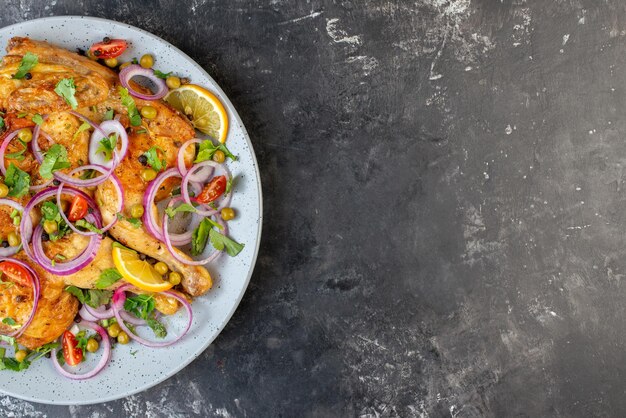 Metade do prato de frango frito delicioso jantar com várias especiarias e alimentos no lado direito em fundo cinza