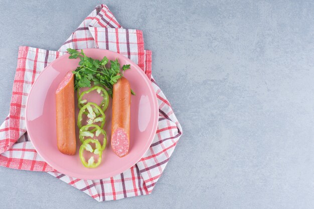 Metade do salame fresco cortado com vegetais na placa-de-rosa.