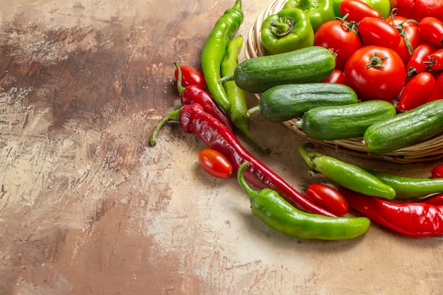 Metade inferior vista vegetais em uma cesta de vime cercada por pimentas e tomates cereja em fundo âmbar