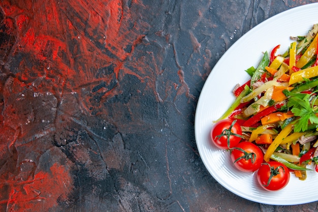 Metade superior vista salada de legumes em prato oval em espaço livre de superfície vermelho escuro