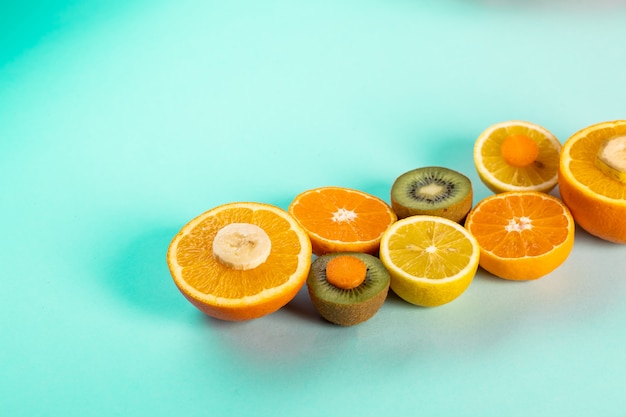 Metades de laranjas kiwi e limões em uma mesa azul