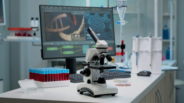Microscópio científico na mesa do laboratório com instrumentos de pesquisa