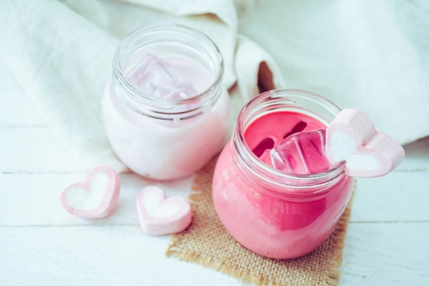 Milk-shake-de-rosa com marshmallows de forma de coração no fundo madeira