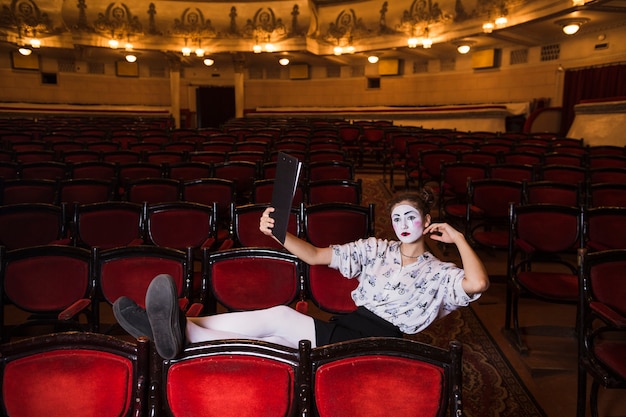 Foto grátis mime feminino com manuscrito sentado na cadeira