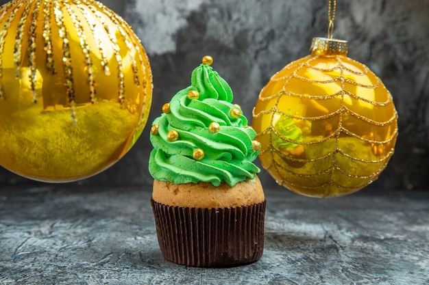 Mini cupcakes coloridos brinquedos de bola de árvore de natal amarela no escuro de vista frontal