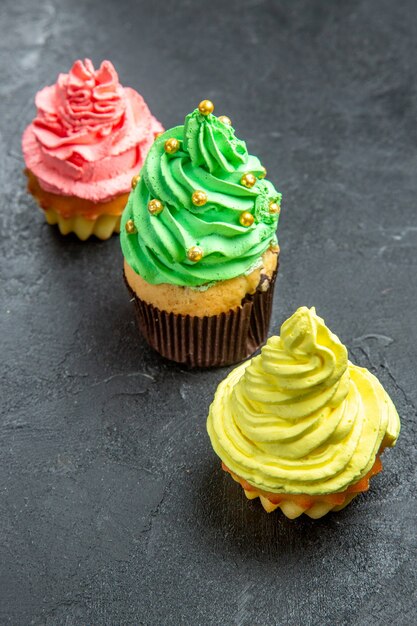 Mini cupcakes coloridos em linha diagonal de vista frontal em um espaço livre escuro