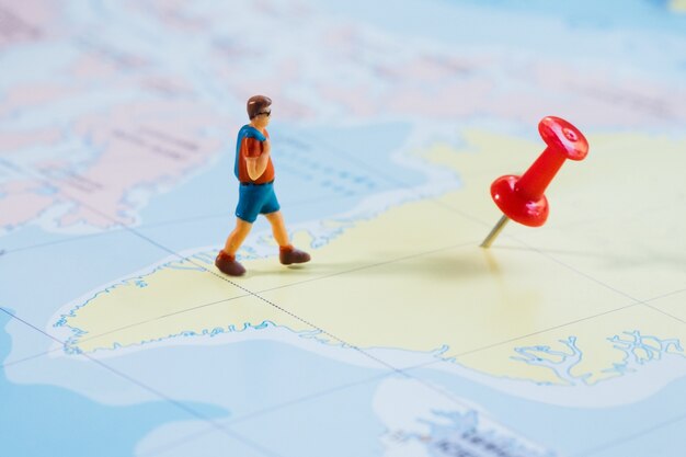 Mini figura viajante com pushpin vermelho e um conceito de viagem de mapa