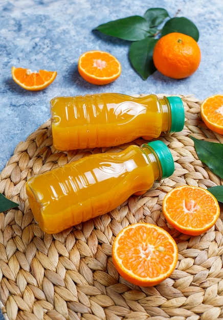 Foto grátis mini garrafas plásticas de suco de laranja orgânico fresco com laranjas e tangerinas cruas