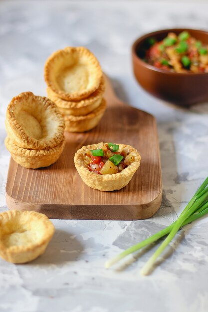 Mini tortas vazias na placa de corte, tornando o processo