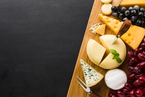Foto grátis mistura plana leiga de queijo gourmet e uvas na tábua com espaço de cópia