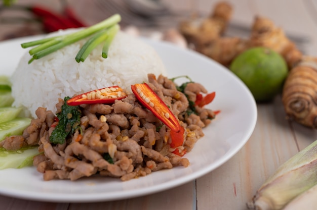 Misture a carne de porco frita com manjericão, ovo frito em um prato branco.