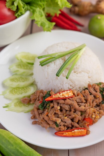 Misture a carne de porco frita com manjericão, ovo frito em um prato branco.