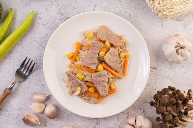 Misture o milho e as cenouras, coloque a carne de porco no prato de madeira.