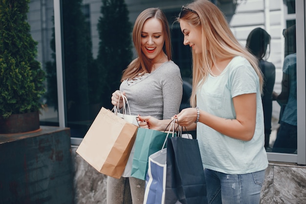 Miúdas giras com sacola de compras em uma cidade