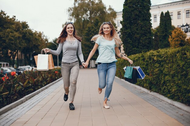 Miúdas giras com sacola de compras em uma cidade