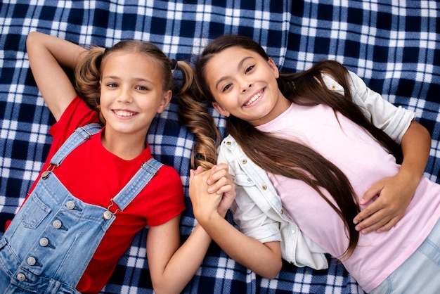 Foto grátis miúdas giras, deitado em um cobertor, mantendo as mãos