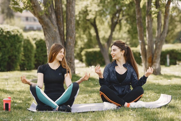 Miúdas giras fazendo yoga em um parque de verão