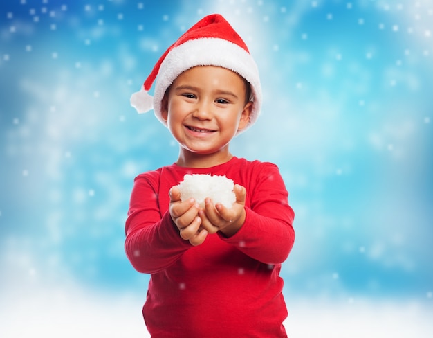 Miúdo de sorriso com neve em suas mãos