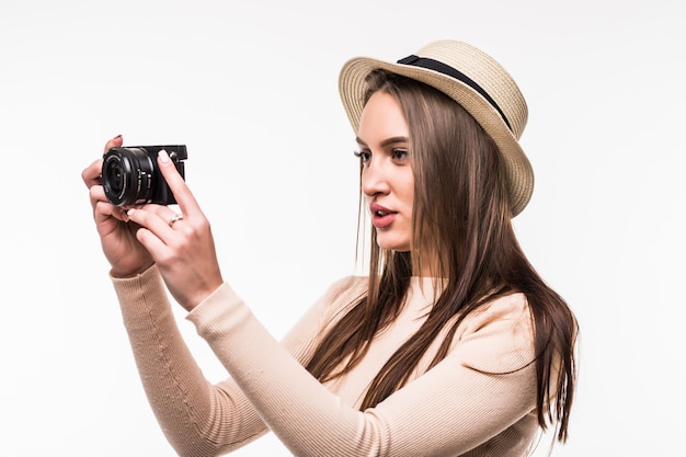 Moça bonita com camiseta brilhante e chapéu faz foto na retrocâmera isolada no branco