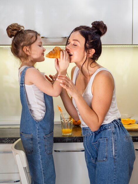 Moça bonito que compartilha do croissant com a mãe