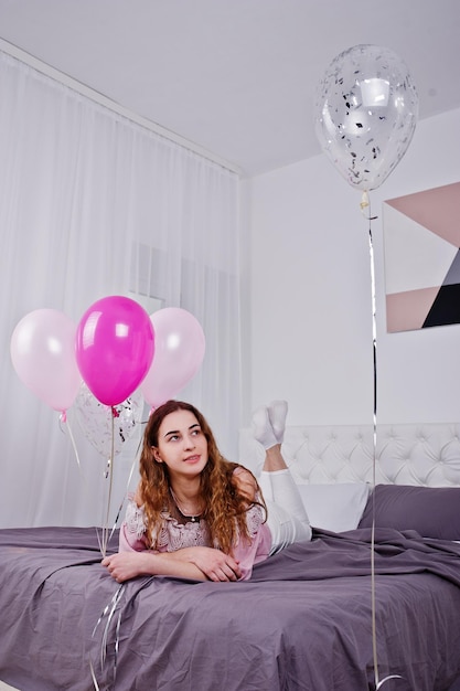 Moça com balões na cama posou na sala de estúdio