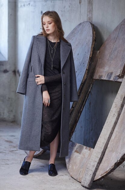 Moça moderna em uma jaqueta longa cinza.