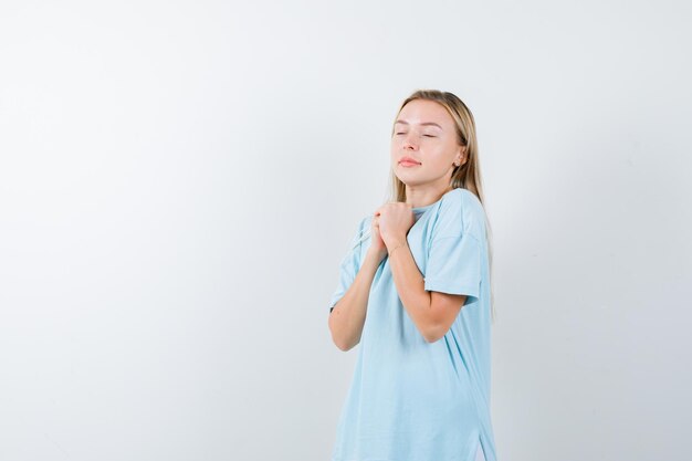 Moça mostrando as mãos postas em um gesto de súplica em uma camiseta e parecendo em paz