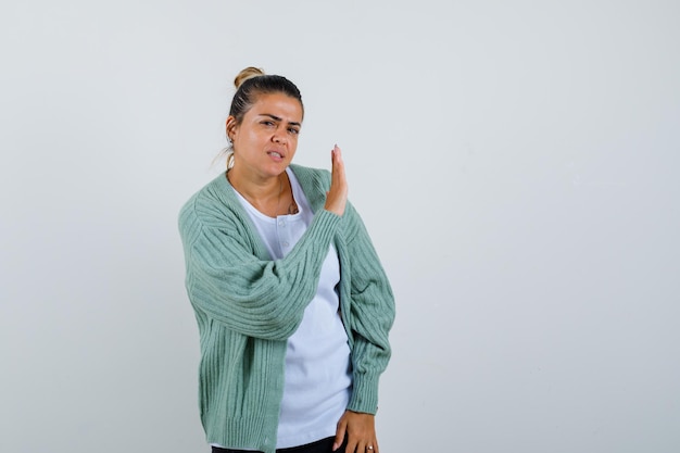 Moça mostrando gesto de parada usando camiseta, jaqueta e parecendo confiante