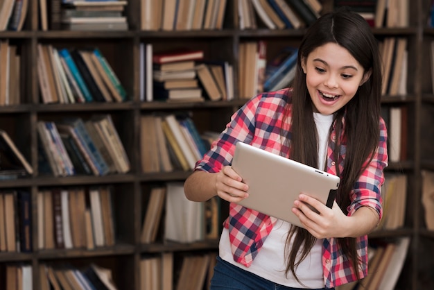 Moça que joga na tabuleta na biblioteca