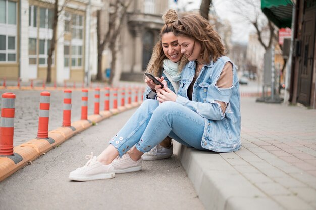 Moças bonitas que navegam no telefone móvel