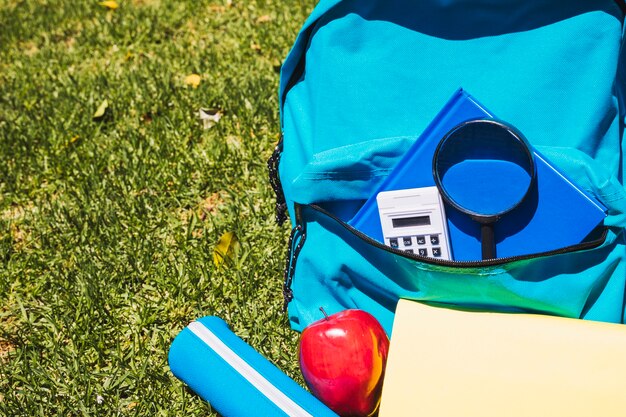 Mochila escolar com material escolar na grama