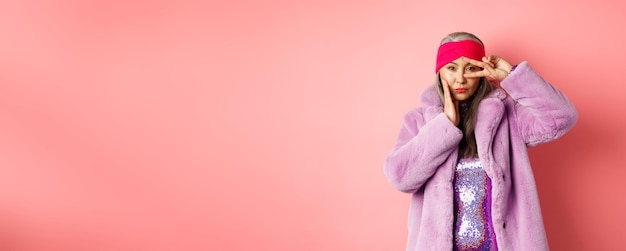 Foto grátis moda e compras linda mulher sênior asiática em elegante casaco de pele falsa e bandana fazendo as pazes