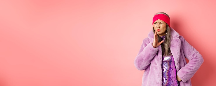 Foto grátis moda e conceito de compras, elegante mulher asiática de meia-idade em roupas de inverno da moda cheira um pouco