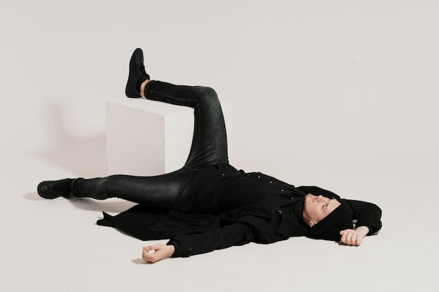 Foto grátis moda homem deitado no branco com uma perna em um cubo