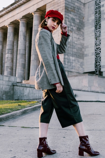 Foto grátis moda jovem mulher com a mão no seu boné vermelho, olhando para a câmera