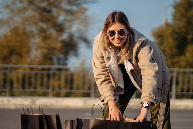 Moda jovem mulher com sacolas de compras no estacionamento