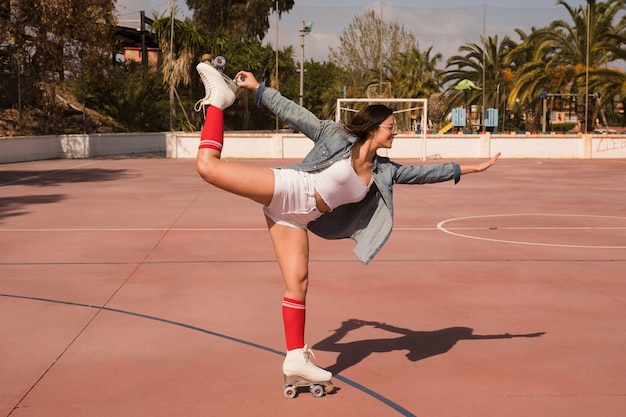 Moda jovem vestindo patim de pé em uma perna sobre o campo de futebol