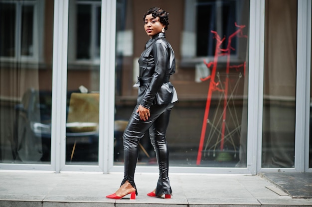 Moda linda mulher afro-americana posando de jaqueta de couro preta e calças na rua