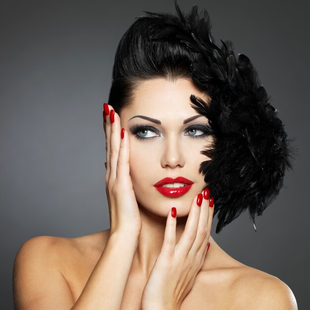 Moda linda mulher com unhas vermelhas, penteado criativo e maquiagem