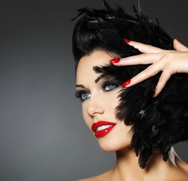 Moda linda mulher com unhas vermelhas, penteado criativo e maquiagem