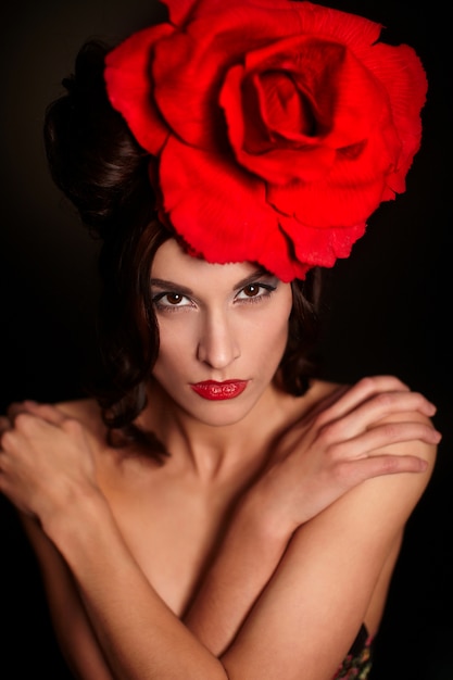 moda mulher bonita com maquiagem brilhante e lábios vermelhos com uma grande rosa vermelha na cabeça
