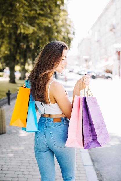 Modelo coquetado posando com sacolas de compras