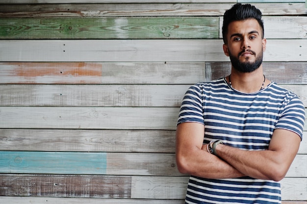 Modelo de homem de barba árabe alto bonito na camisa despojada posou ao ar livre contra fundo de madeira cara árabe na moda