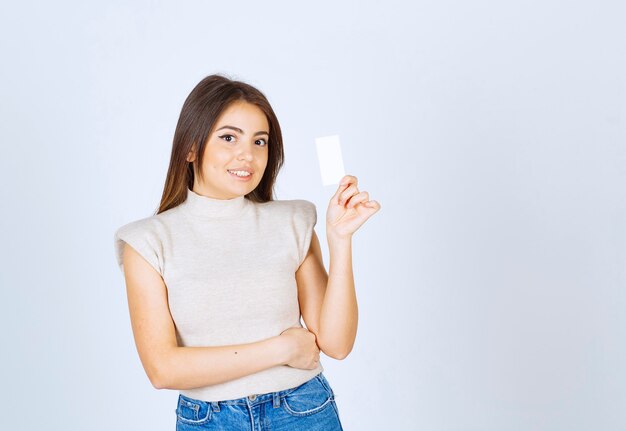 Modelo de mulher bonita sorridente em pé e mostrando o cartão.