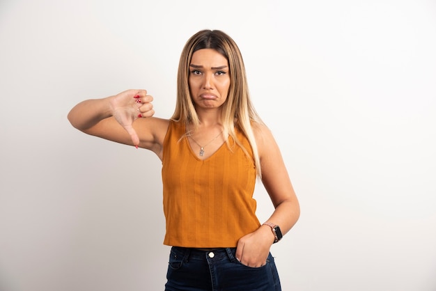 Modelo de mulher jovem com roupas casuais, mostrando o polegar para baixo e posando