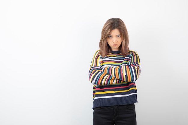 Modelo de mulher jovem e bonita em pé e posando com os braços cruzados.