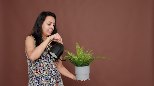 Modelo feliz segurando o vaso de flores e regando a planta verde, jardinagem e cuidando da planta de casa florescendo. cultivo natural e hobby de botânica, derramando água da lata para florescer a flora natural.