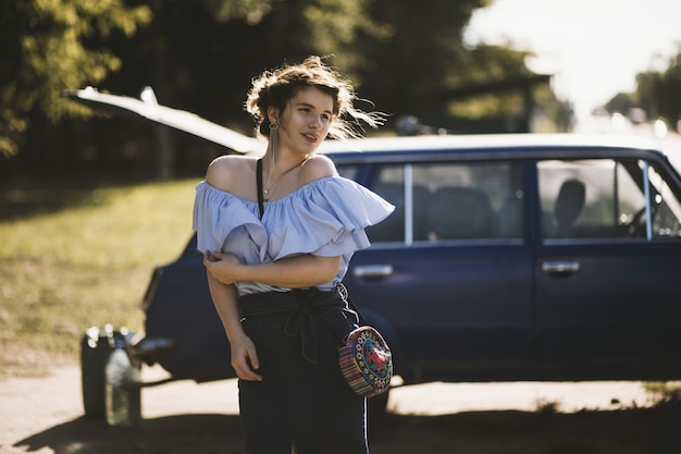 modelo feminino atraente em um vestido fora do ombro se passando perto de um veículo