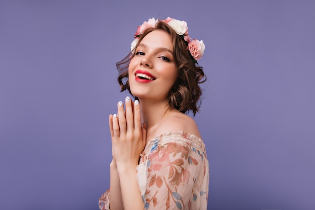 Modelo feminino branco refinado em roupa romântica rindo. desgraçada garota de cabelos curtos com flores na cabeça sorrindo.