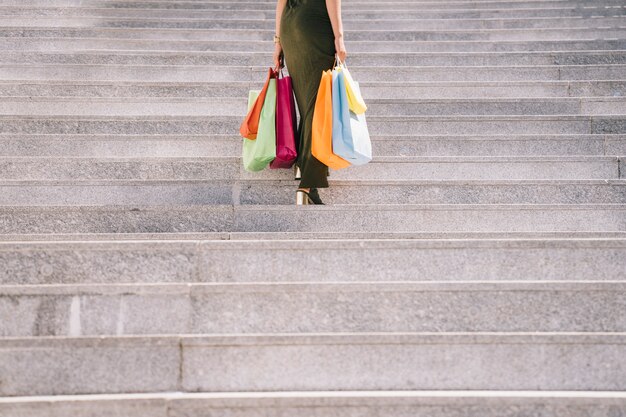 Modelo feminino com sacolas de compras subindo no andar de cima